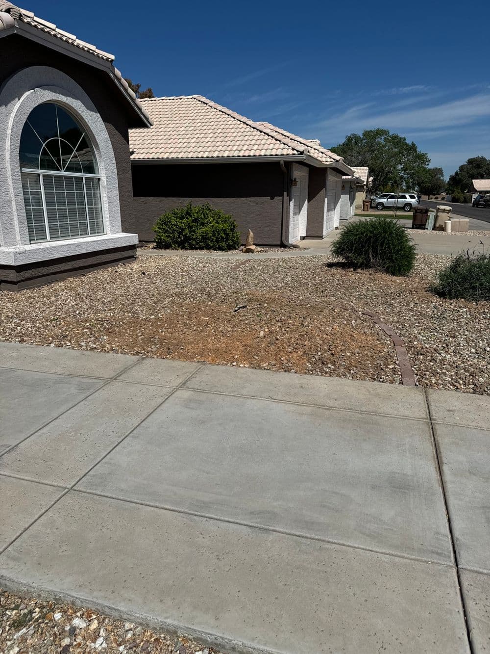 Residential home with a landscaped yard and sidewalk under a clear blue sky.
